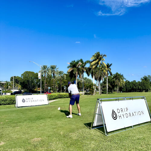 man playing golf, drip hydration's logo in the back