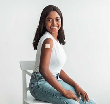 woman with a patch on her arm from a vaccine, smiling